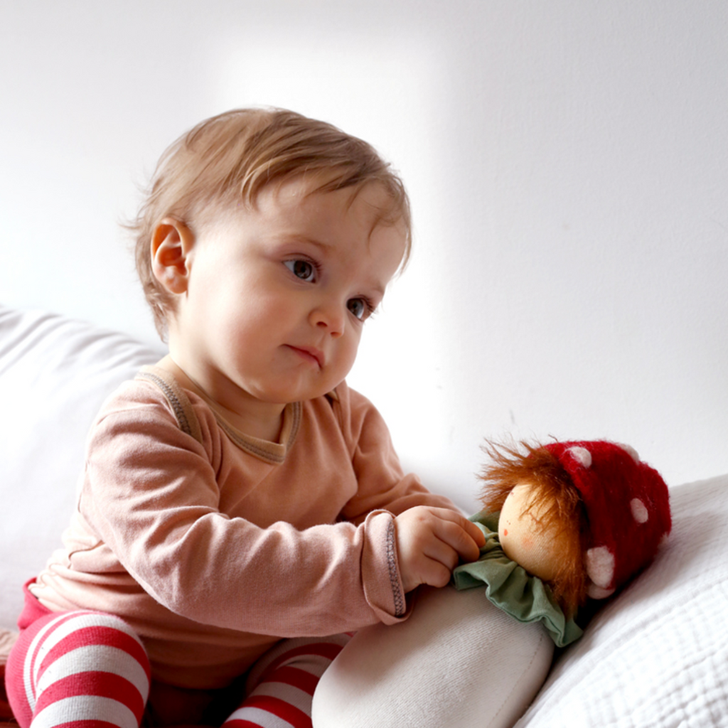Baby holding a organic music box.  Nanchen Natur Perfect for baby to drift of to fairytale dreamland with a sweet, soft, cuddly friend. Lovingly handmade to be just right for tiny hands to grasp and hold. Soothing, cozy, wonderfully soft and adorable to look at. Soft music will soothe and comfort. Great at home or on the go and a perfect gift! Each sold separately.